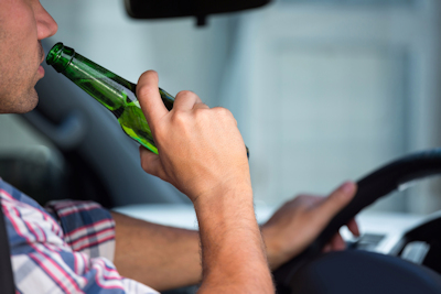 Man drinking a beer while behind steering wheel